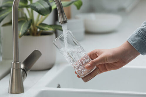 Woman filling a glass with clean, filtered water.